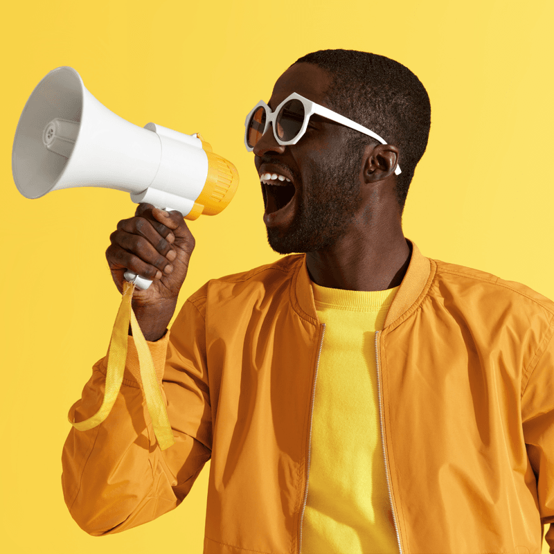 man dressed in yellow screaming an announcement into a megaphone